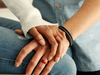two hands wresting on a leg with silicone rings on their fingers