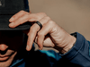 Man grabbing the brim of his hat with his hand and a silicone ring on his finger